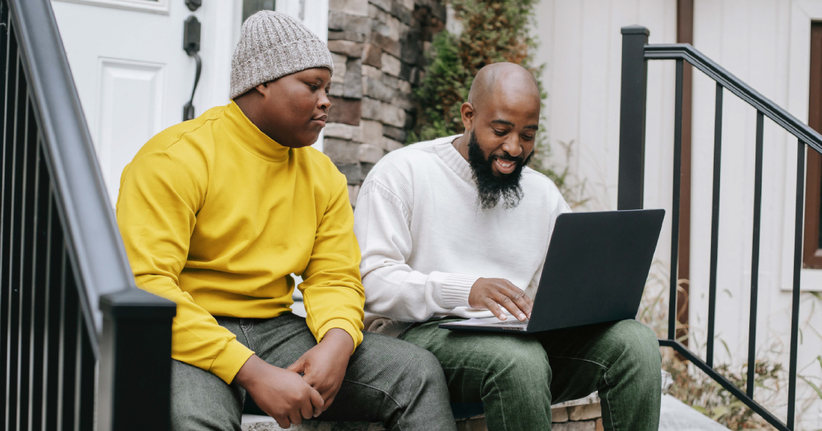 Father and teenage son using a computer to research their college visit