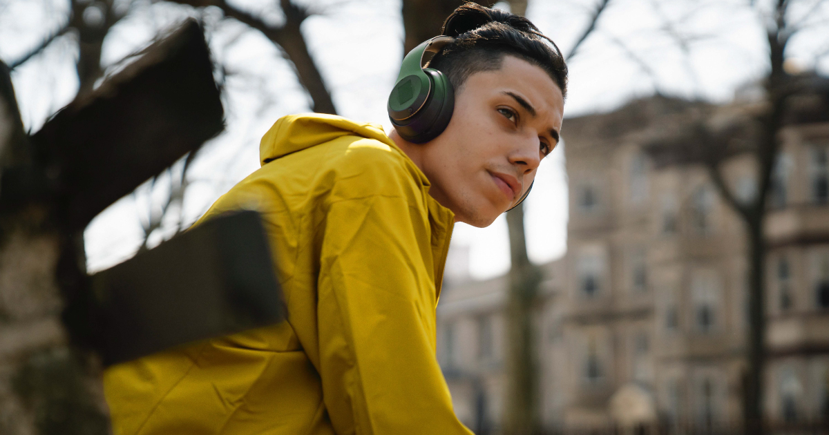 High school student sitting on a park bench wearing music headphones