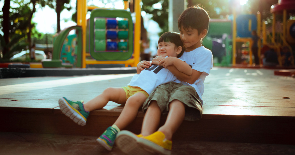 Two brothers sitting together in a playground