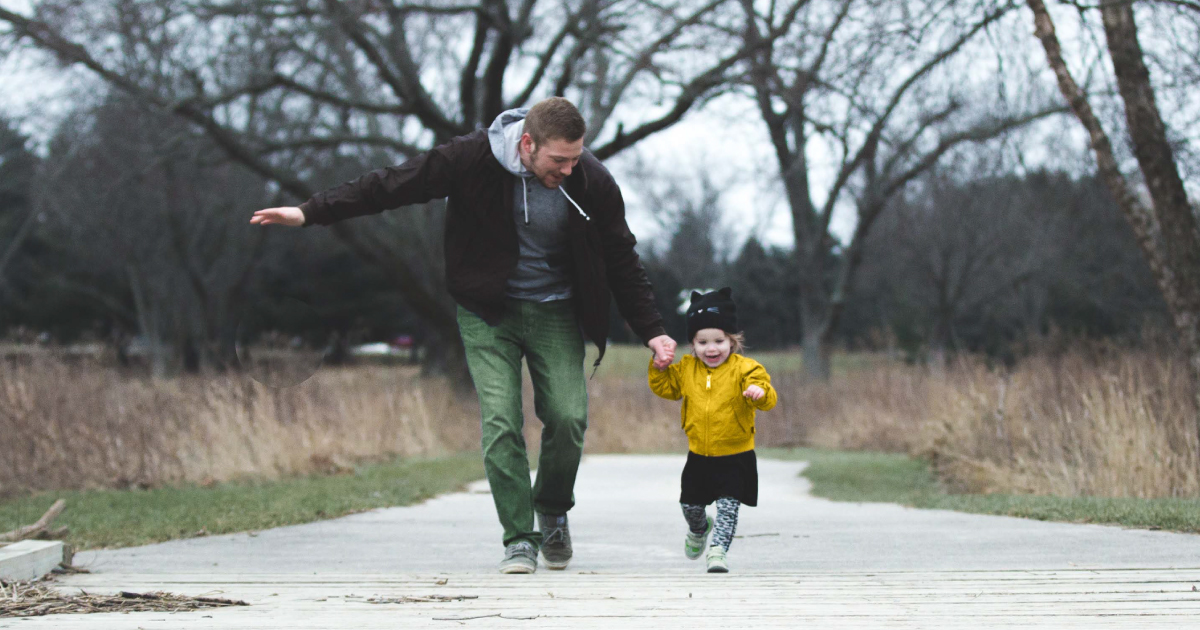 Father running outside with his toddler daughter