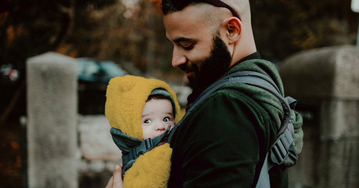 Father holding his infant in a front baby carrier