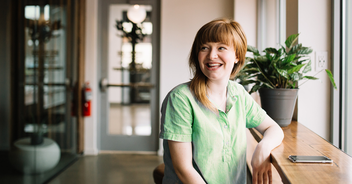 Young woman sitting in a nondescript room smiling