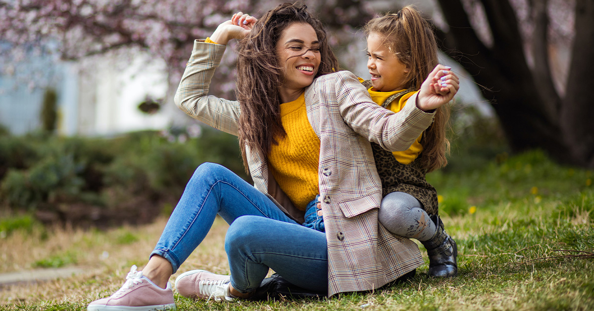 Mother playing with young daughter outside