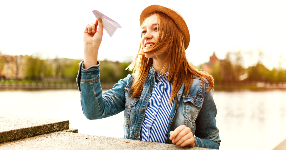 girl throwing paper airplane